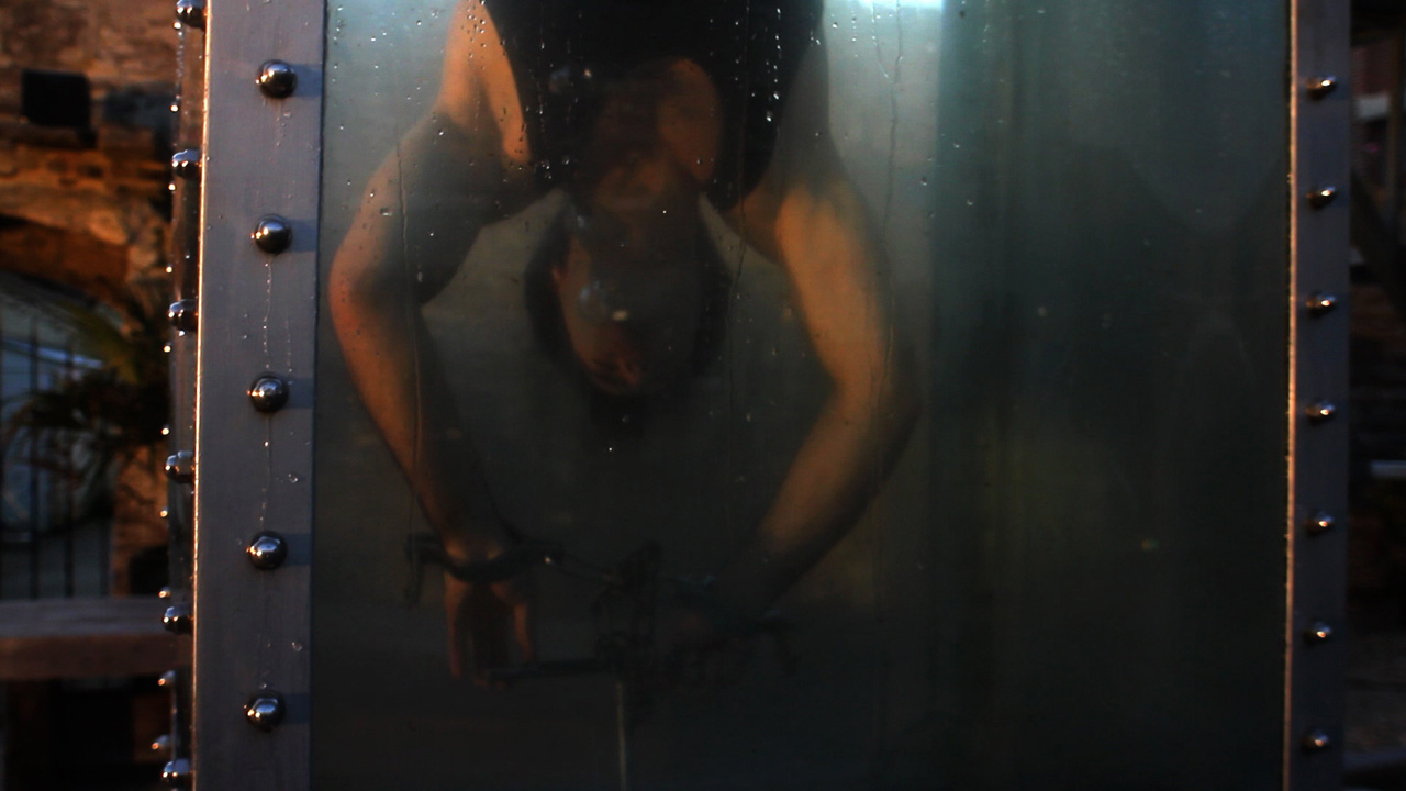 Ramin Karimloo as Houdini trying to get out of the water while handcuffed.